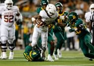 Jonathon Brooks #24 of the Texas Longhorns gives a stiff arm to Devin Lemear #20 of the Baylor Bears